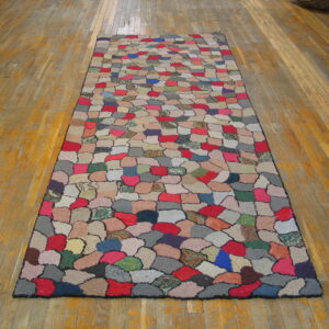 Multicolored runner rug with a patchwork of red, blue, gray, and beige patches on hardwood.