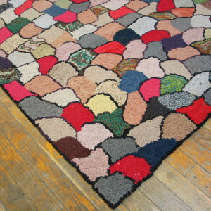 Close-up of a high-pile rug with irregular, multicolored patches on worn wood plank flooring.