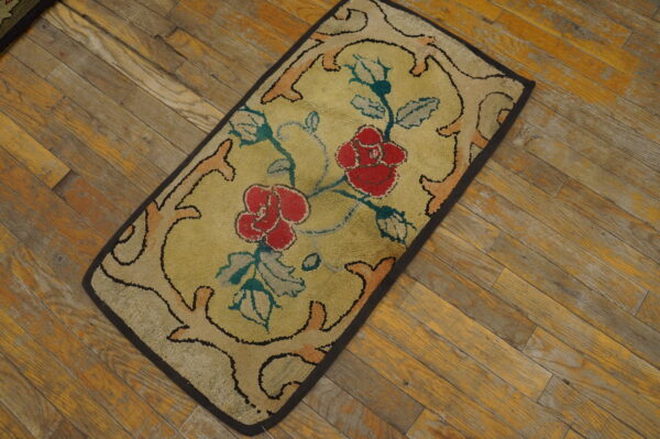 Low-pile rectangular rug featuring red roses and teal foliage on a yellow field over wood flooring.