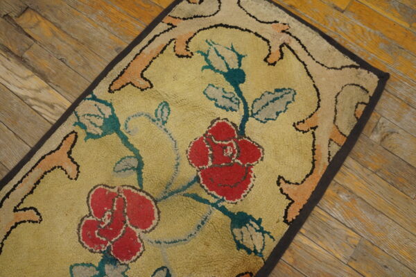 Textured rug with large red roses, teal stems, and a gold field on distressed plank wood flooring.