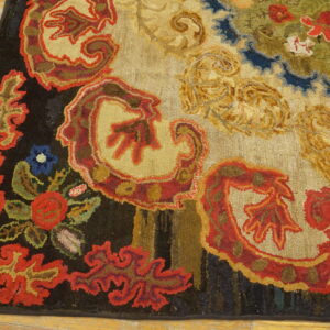 Textured rug featuring large, scrolling floral patterns in red, gold, green, and blue on light wood flooring.