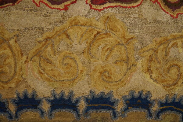 Highly textured rug detail features large golden ornamental scrolls and deep blue stylized border motifs.