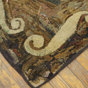 Textured rug corner showing cream scroll patterns and variegated browns on wide plank wood floor.