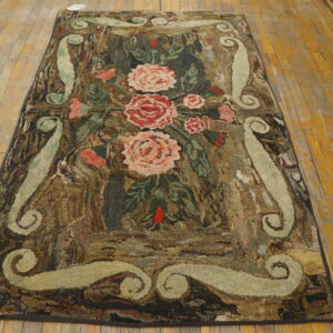 Textured rug with pink floral motifs and pale green scrolls laid on shiny wood plank flooring.