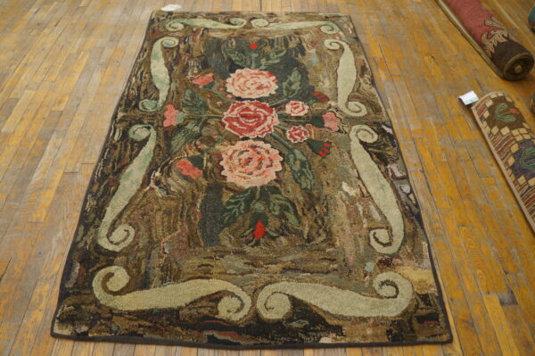 Textured rug with pink floral motifs and pale green scrolls laid on shiny wood plank flooring.