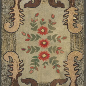 Textured rug with a floral center in red and green, framed by scrolling brown motifs and a dark speckled border.