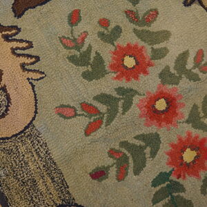 A highly textured rug with a sage green background, featuring red flowers and a tan scroll border.