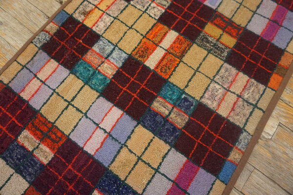 Textured, multicolored rug featuring a dense diamond argyle pattern on light, distressed wood plank flooring.