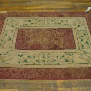 Rectangular rug with a mottled reddish-brown center and an inner cream border with green scrollwork on wood floors.
