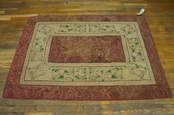 Rectangular rug with a mottled reddish-brown center and an inner cream border with green scrollwork on wood floors.