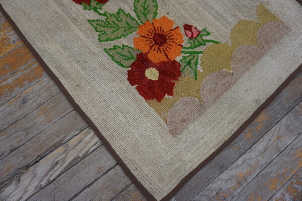 Textured beige rug featuring bright red and orange floral designs on weathered gray wood flooring.
