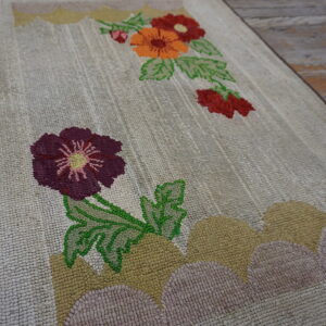 Hooked cream runner rug with purple, orange, and green floral accents over rustic wooden flooring.
