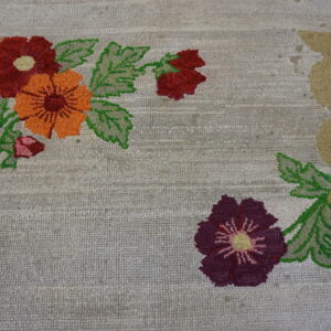 Looped rug featuring large orange, red, and purple flowers with a scalloped gold and pink border.