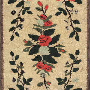 A textured beige rug features a red, green, and black floral vine design framing a central bouquet.