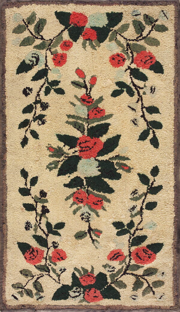 A textured beige rug features a red, green, and black floral vine design framing a central bouquet.