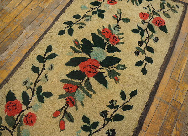 A textured tan runner rug displays red and green floral vines on distressed hardwood.