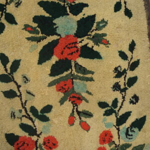 Highly textured rug runner featuring coral, green, and blue floral motifs on a tan ground, laid on distressed wood planks.