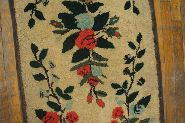 Highly textured rug runner featuring coral, green, and blue floral motifs on a tan ground, laid on distressed wood planks.
