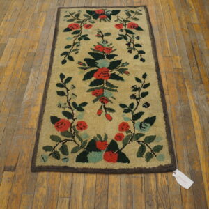 Tan high-pile rug with red and green scrolling floral motifs on distressed hardwood planks.