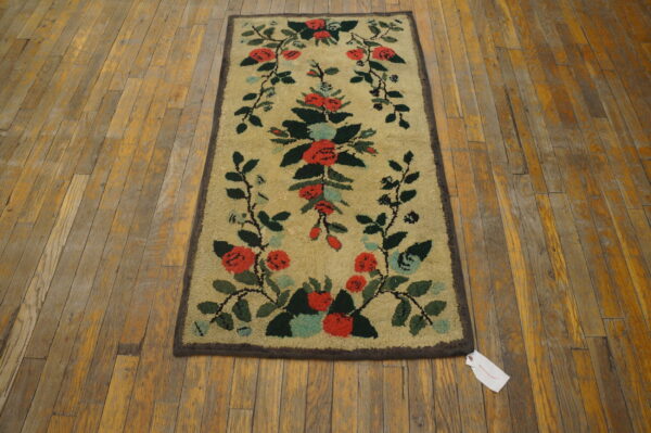 Tan high-pile rug with red and green scrolling floral motifs on distressed hardwood planks.