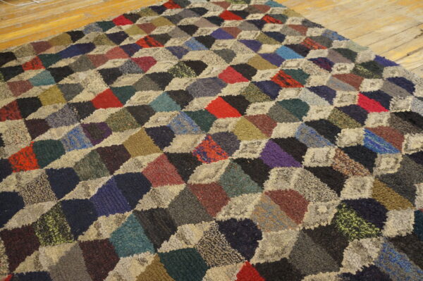 High-pile multicolored rug with a geometric cube patchwork design on wood planks.