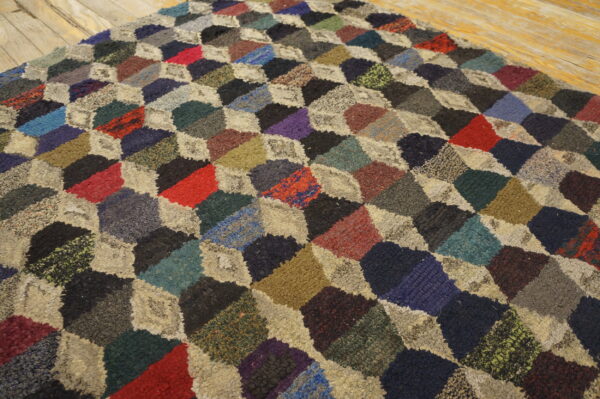 Textured multicolored rug featuring a geometric patchwork design of diamonds on rustic wood flooring.