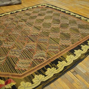 Textured olive green and black rug with geometric patterns and a gold leaf border on a hardwood floor.