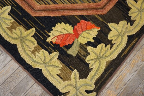 Hooked rug detail showing pale yellow and red florals against a dark ground, lying on light grey wood planks.