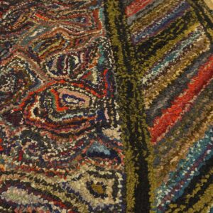 Multicolor textured rug detail featuring abstract swirls and strong diagonal stripes on wood floorboards.