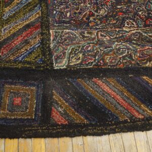 Dark, textured rug featuring block patterns, colorful stripes, and abstract designs against yellow wood planks.