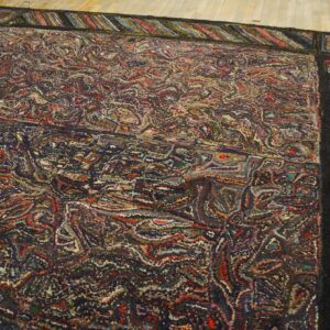 Textured multicolor rug with a dense, chaotic field pattern and a striped border on light wooden planks.