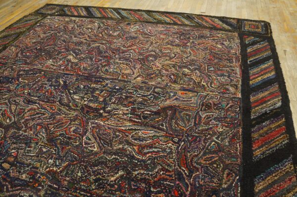 Textured multicolor rug with a dense, chaotic field pattern and a striped border on light wooden planks.