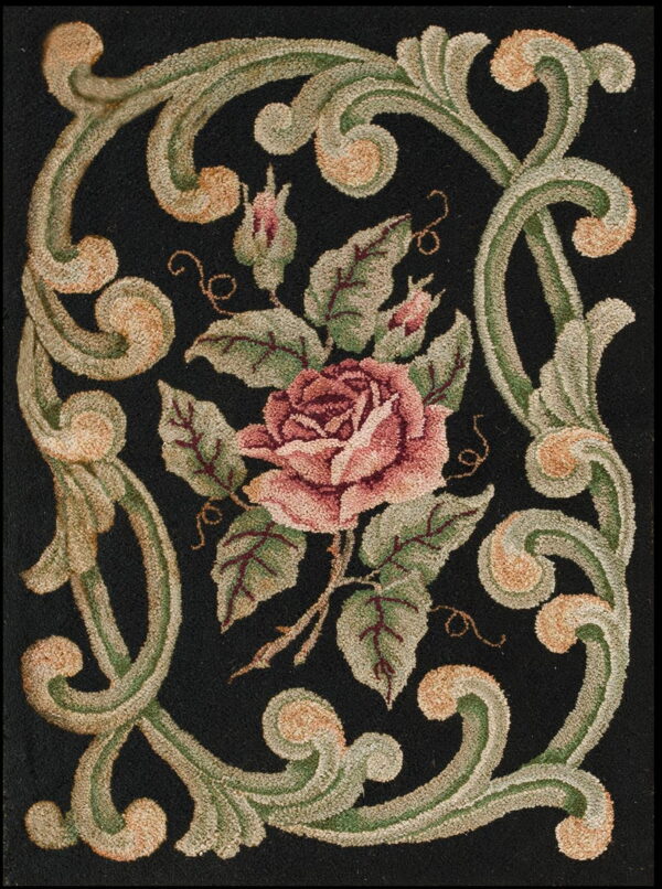 Close up of a textured rug showing a pink rose and green scrolling vines on a deep black background.