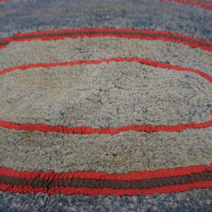 Textured blue and gray shag rug showing concentric rings defined by vibrant red and dark gray stripes.
