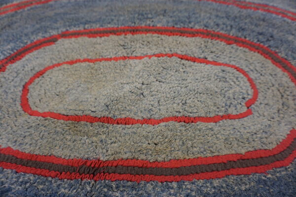 Textured blue and gray shag rug showing concentric rings defined by vibrant red and dark gray stripes.