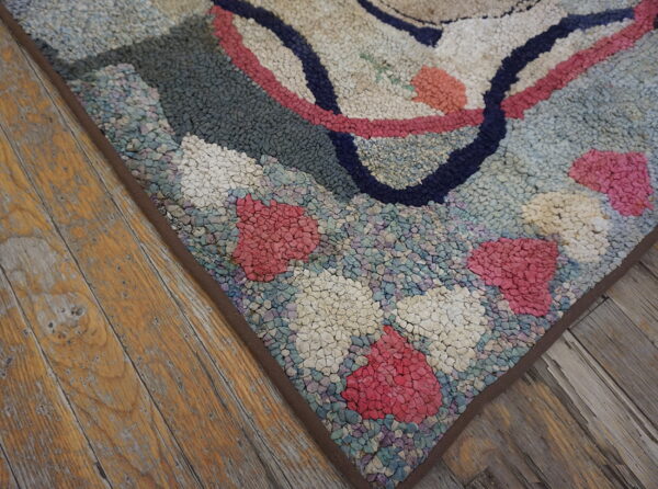 Chunky textured rug in pink, navy, and cream colors rests on distressed wooden flooring.