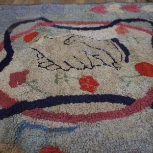 Chunky loop pile rug featuring a cream central handshake motif bordered by navy and pink stripes.