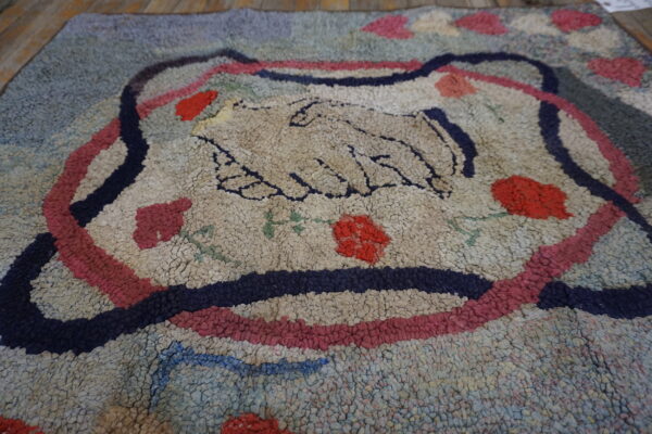 Chunky loop pile rug featuring a cream central handshake motif bordered by navy and pink stripes.