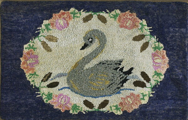Textured dark blue rug featuring a gray swan in a floral medallion with pink and green accents.