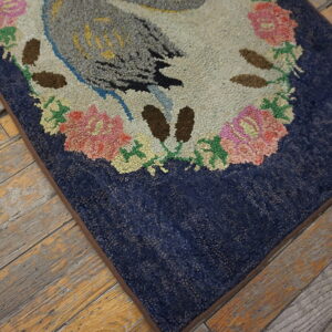 Textured rug with a bird and floral pattern on a navy background, resting on aged wood planks.
