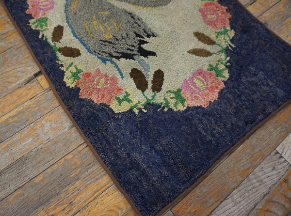 Textured rug with a bird and floral pattern on a navy background, resting on aged wood planks.