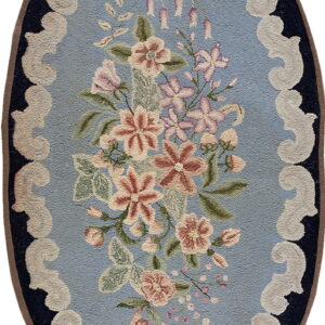 Oval rug featuring a floral bouquet on a light blue field surrounded by creamy white scallops and a navy border.