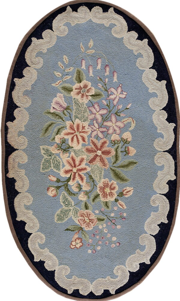 Oval rug featuring a floral bouquet on a light blue field surrounded by creamy white scallops and a navy border.