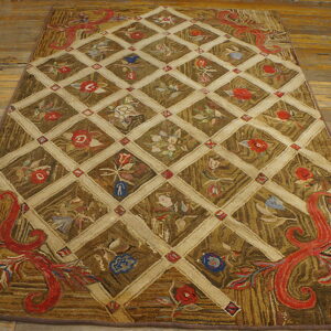 Brown and gold textured rug with a cream lattice pattern, colorful floral motifs, and large red scrolled corners on wood floor.