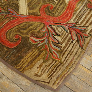 A high-texture hooked rug displays scrolling red and earthy brown botanical patterns on weathered plank flooring.