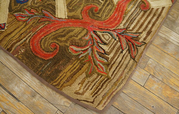 A high-texture hooked rug displays scrolling red and earthy brown botanical patterns on weathered plank flooring.