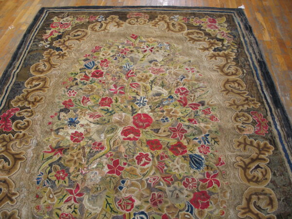 An ornate, multi-color floral rug with a sculpted border rests on wide plank wood flooring.
