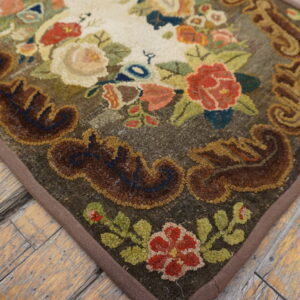 A heavily textured floral rug with red, cream, and brown colors rests on weathered wooden flooring.