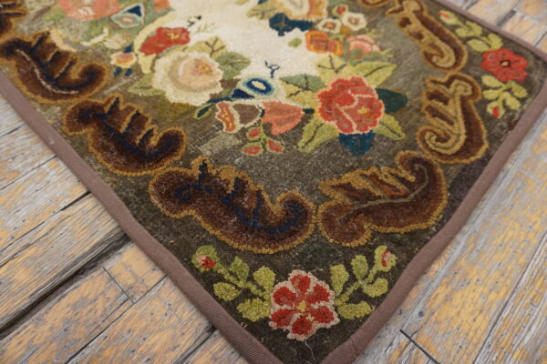 A heavily textured floral rug with red, cream, and brown colors rests on weathered wooden flooring.