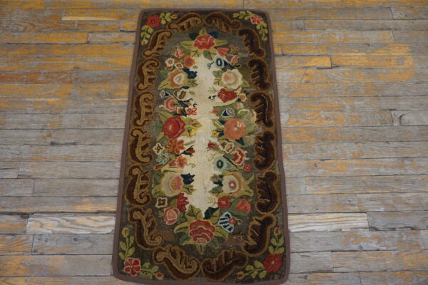 Highly textured floral runner rug with vibrant colors and dark scrolled borders rests on distressed wood flooring.